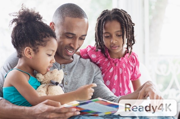 A black father reads to his two young daughters; all are smiling; Ready4K logo is watermarked on image. 
