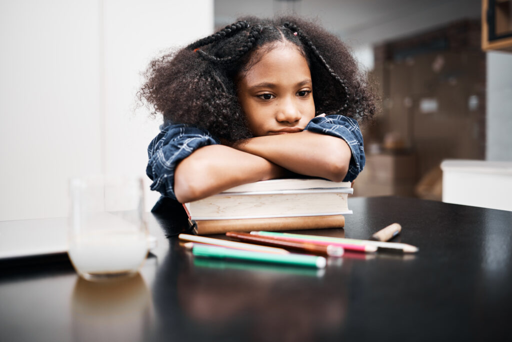 Late elementary school student frowns with concern while resting arms on top of books.