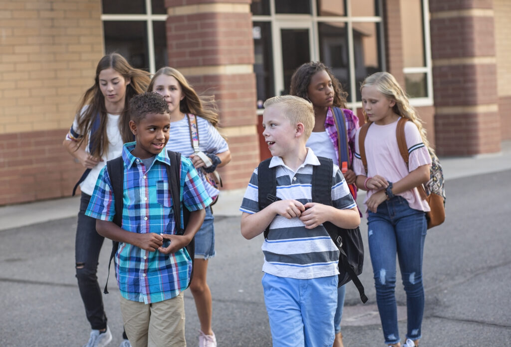Diverse group of late elementary school students walking together on campus.