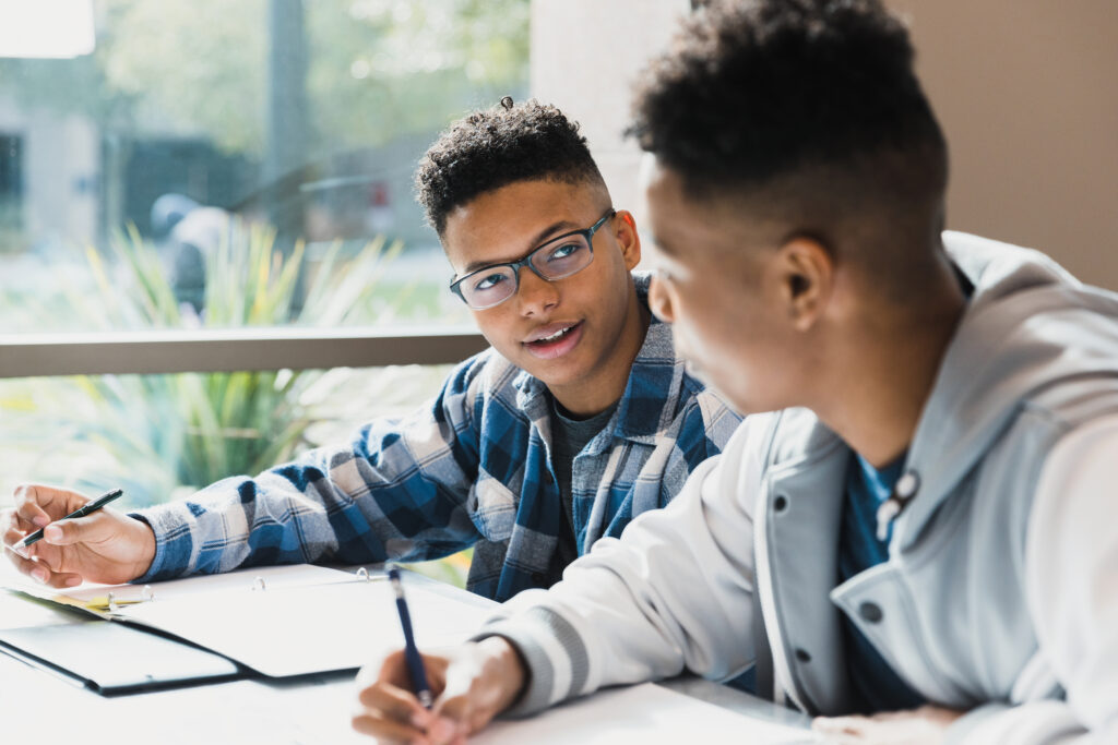 A teenage black boy talks to his friend as they study for a test together.